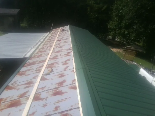 Old rusted panels beside newly installed green metal roofing — Wind Damage Roof Repair by Roofing Brothers in Lone Wolf