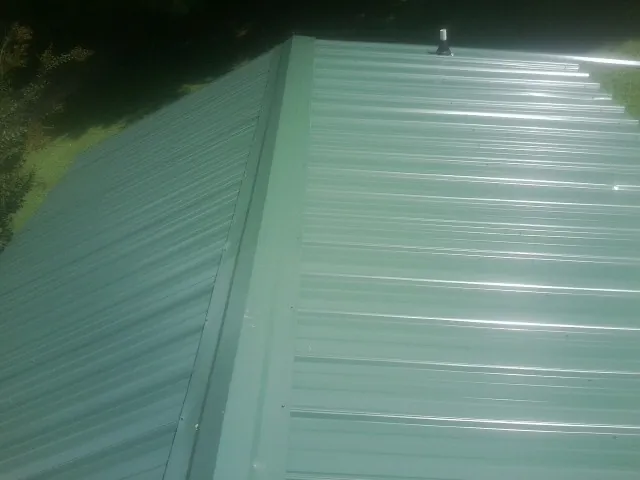 New green metal panels meeting at the ridge of a roof — Flat Roof Repair work by our crew in Lone Wolf