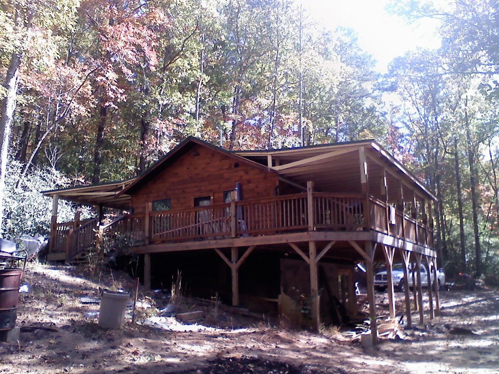 Log cabin with a wraparound porch and metal roof in the fall in Lone Wolf