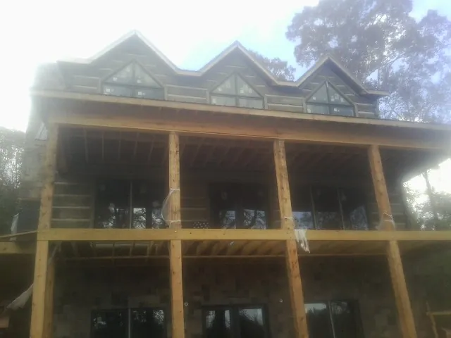 Dormers and porch framing on a large log home under construction — Roof Coating work by our crew in Lone Wolf