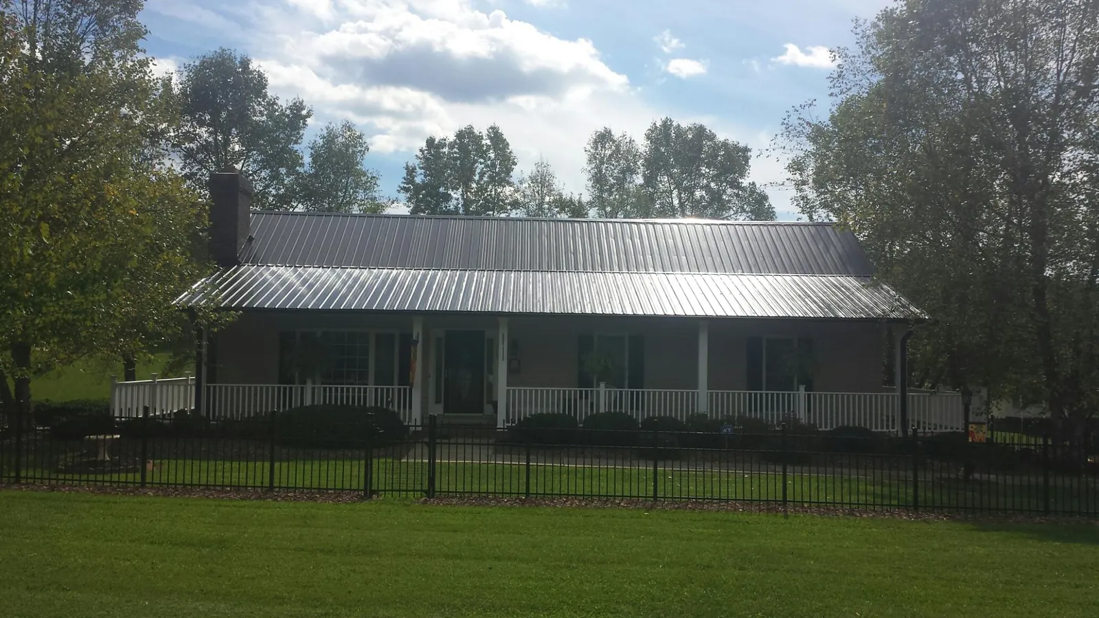 Gray metal roof on a brick ranch with a full width front porch — Gutter Guard Installation work by our crew in Lone Wolf