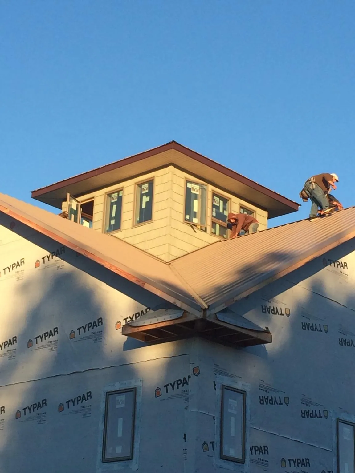 Roofers working around a rooftop cupola on a new metal roof at sunset — Roof Waterproofing in Lone Wolf by Roofing Brothers